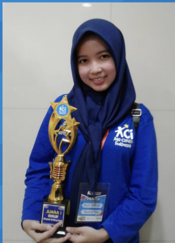 Kak Wahyu mengenakan seragam biru ACI sambil memegang piala prestasi